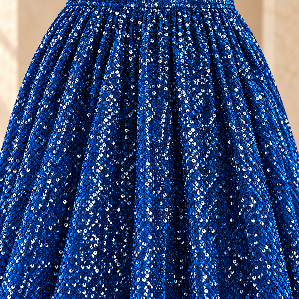 Close-up of royal blue sequins and vertical folds on the skirt of the MX340 evening gown.